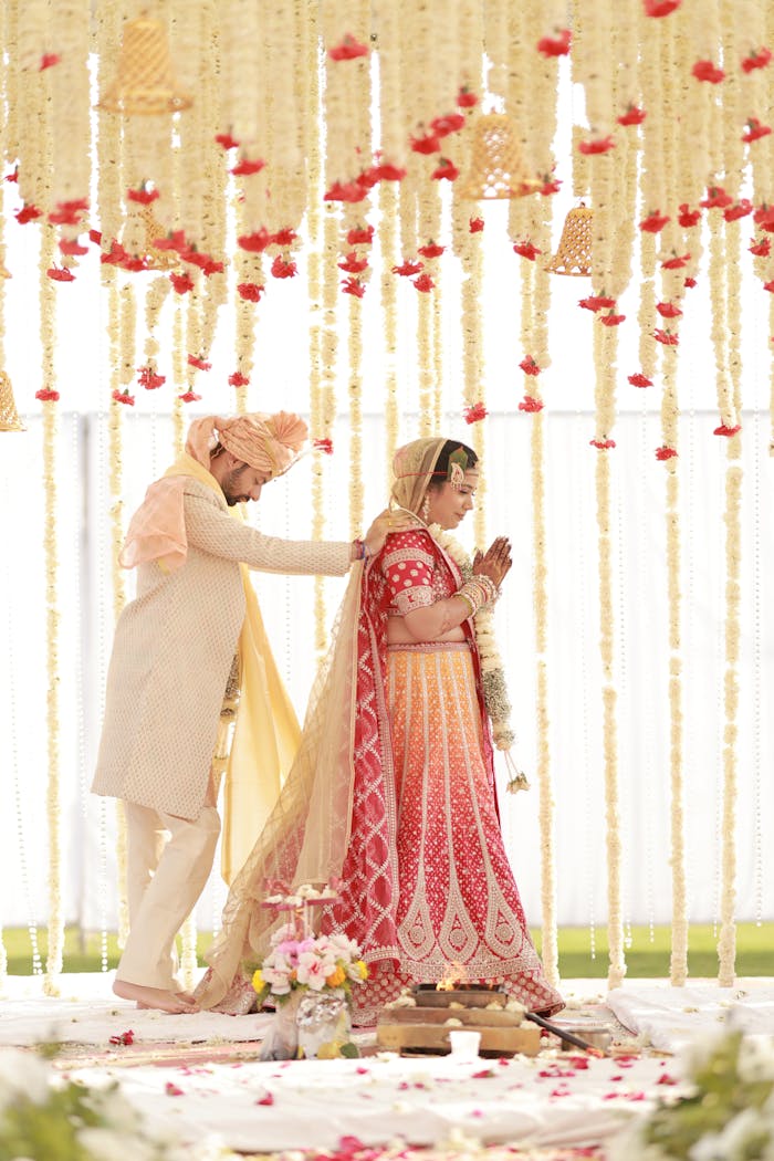 Crafting Captivating Headlines: Your awesome post title goes here Bride and groom performing a traditional Indian wedding ceremony under decorative floral arrangements.